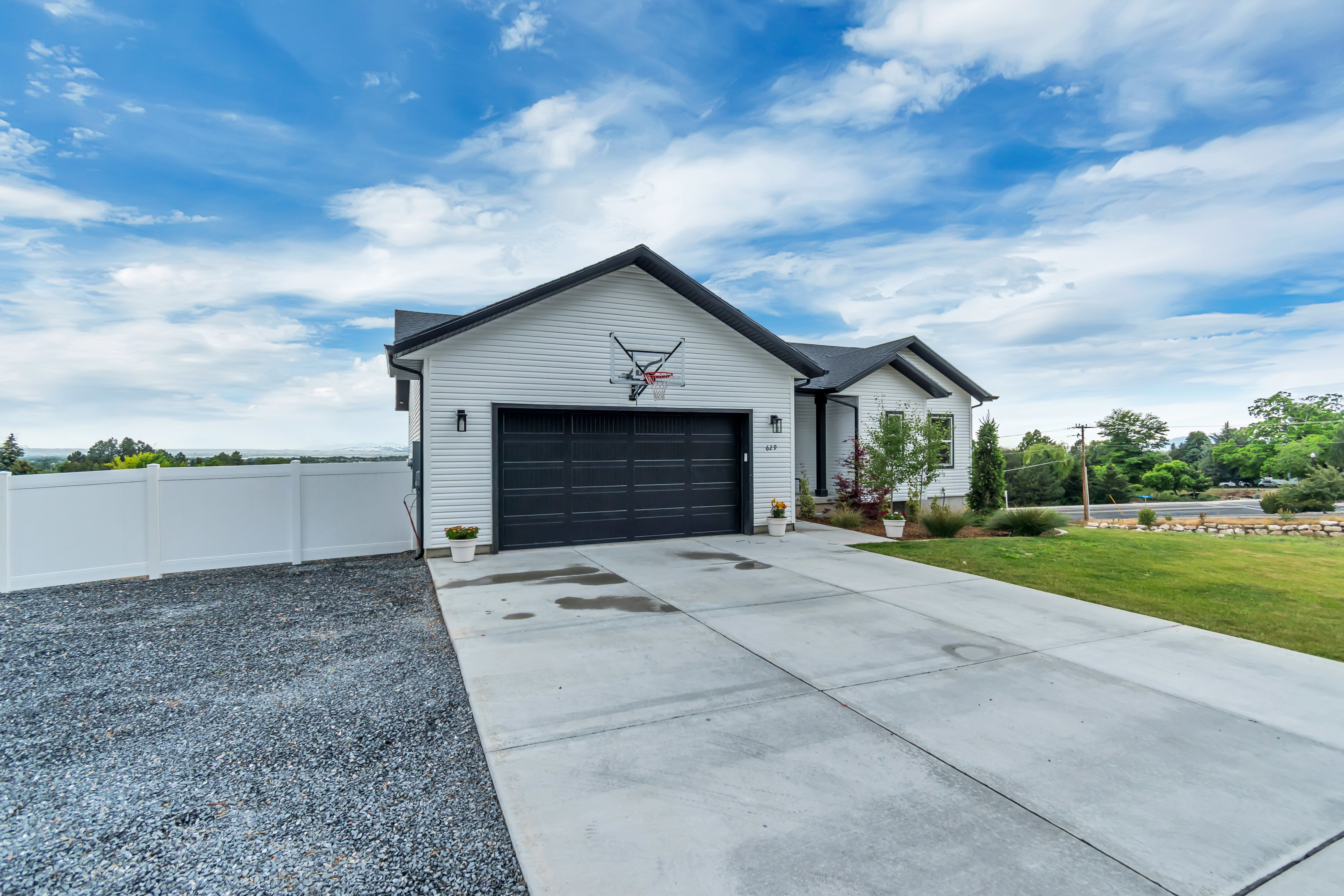 Modern white siding exterior with a black roof and garage door