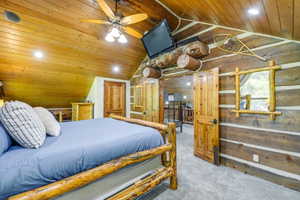 Rustic bedroom featuring log walls and a wood-paneled ceiling with recessed lighting