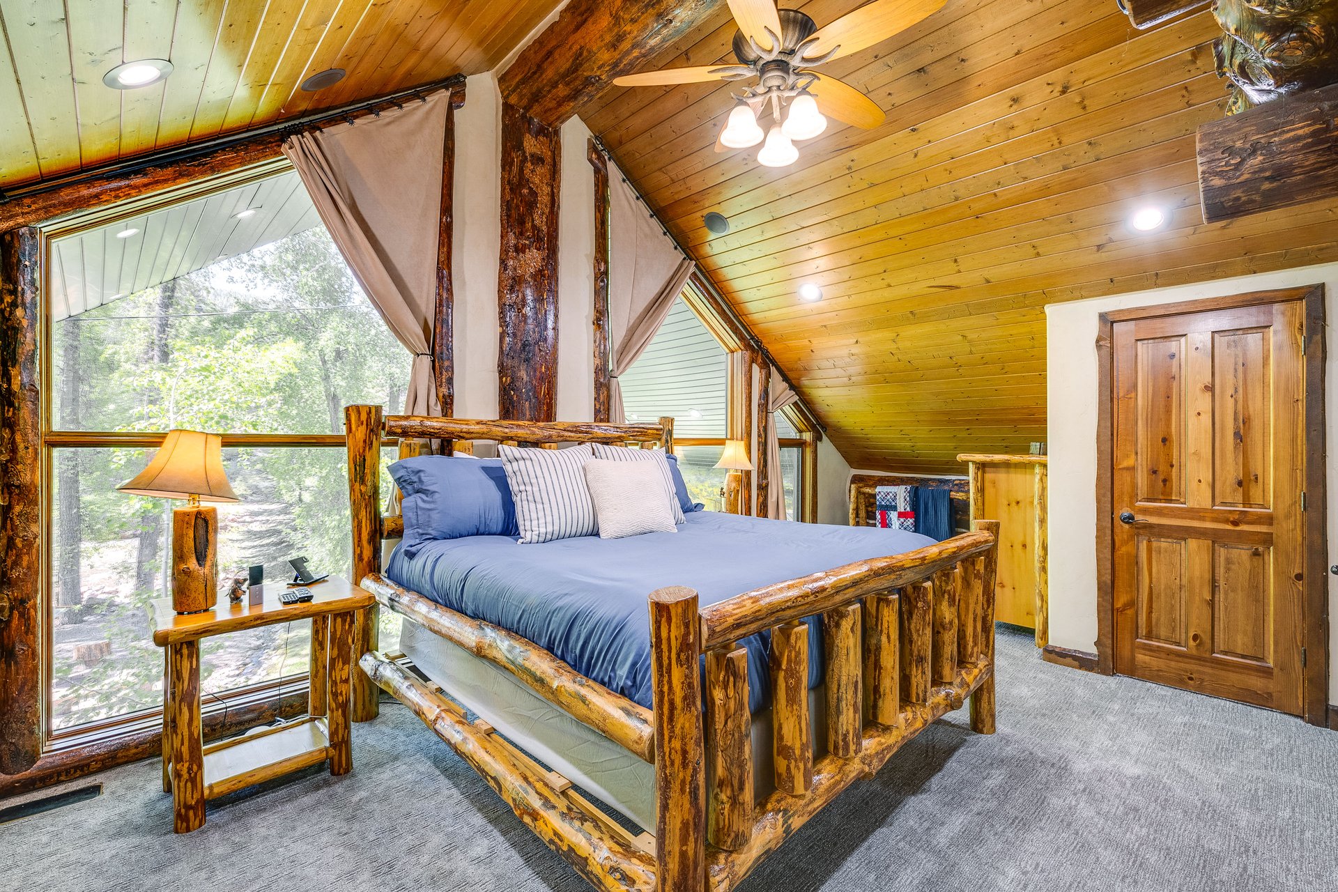 Room featuring a wood-paneled sloped ceiling, wood-finish flooring, and expansive windows
