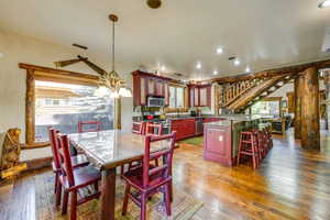 Open-concept kitchen and dining area featuring rich wood-finish flooring, a full suite of stainless steel appliances, a kitchen island with counter seating, and log-style architectural elements