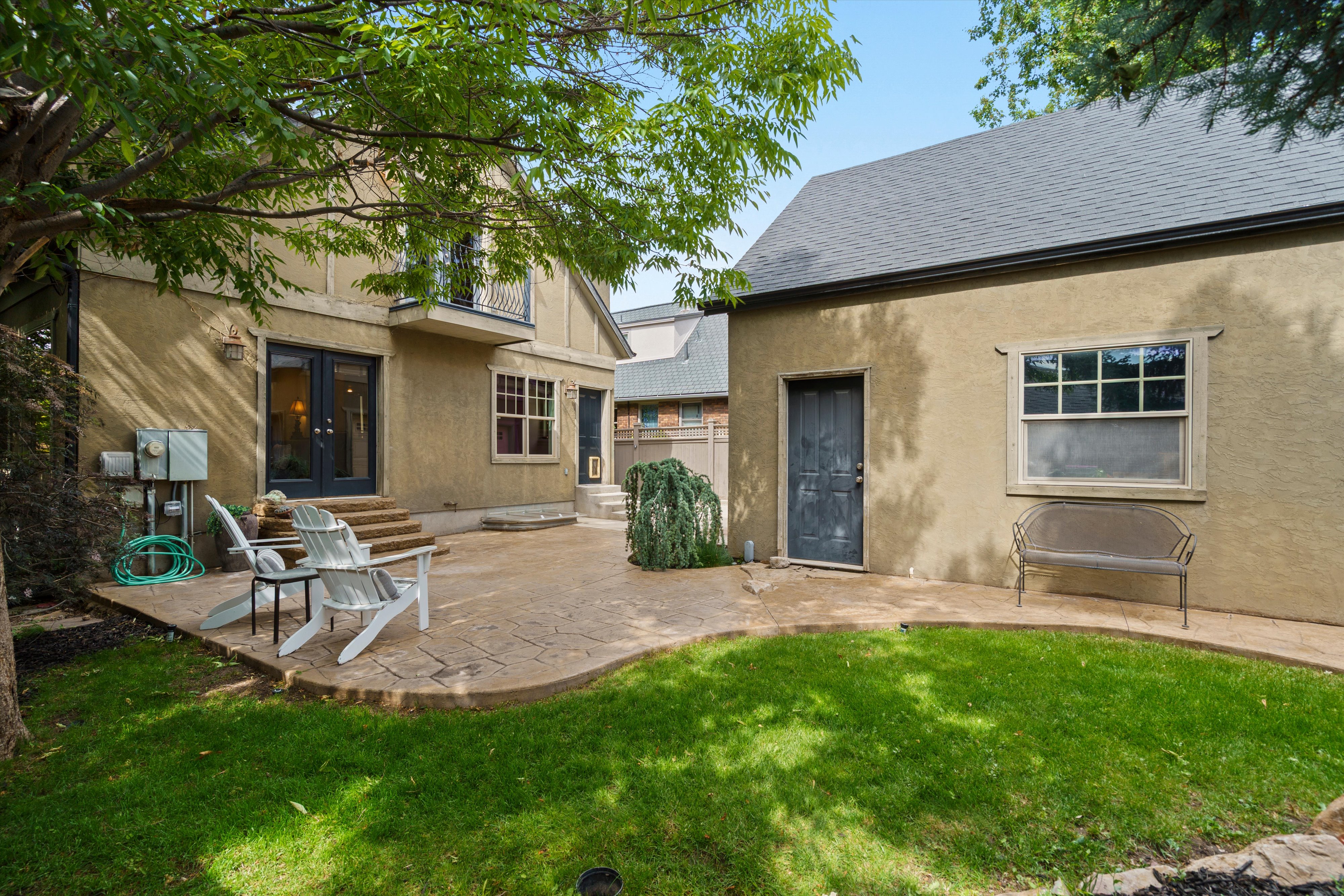 Expansive stamped concrete patio framed by a manicured lawn and mature trees
