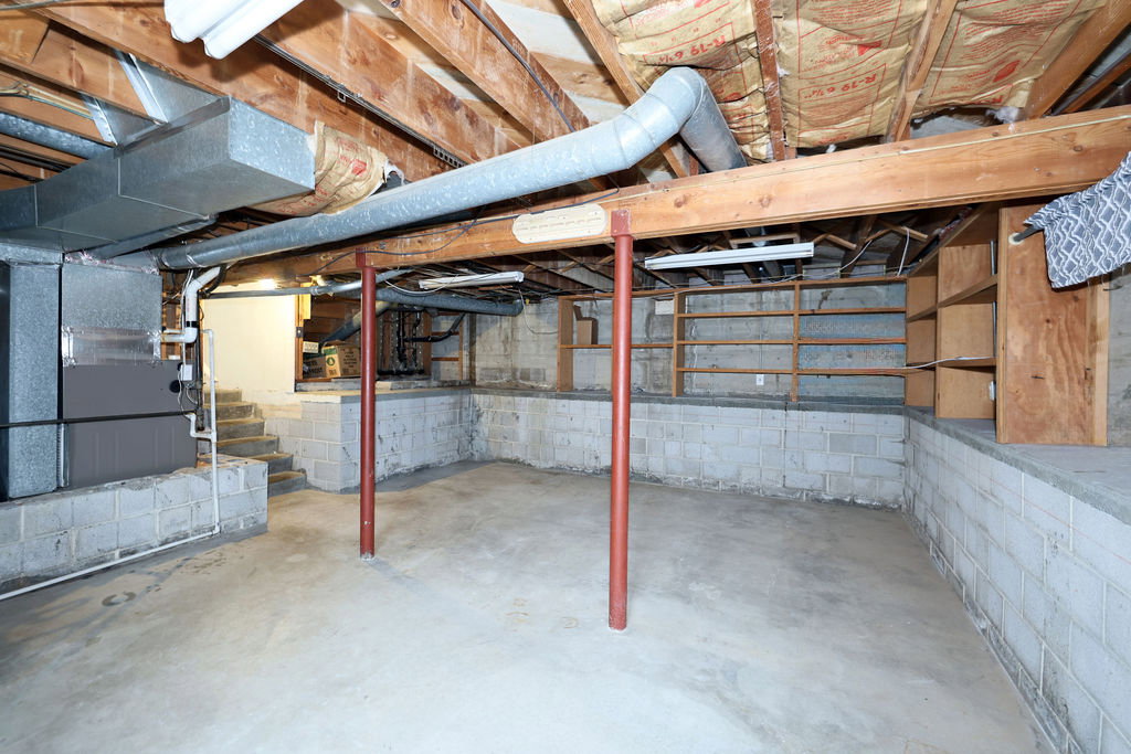 Unfinished basement space featuring exposed wood joists and concrete flooring