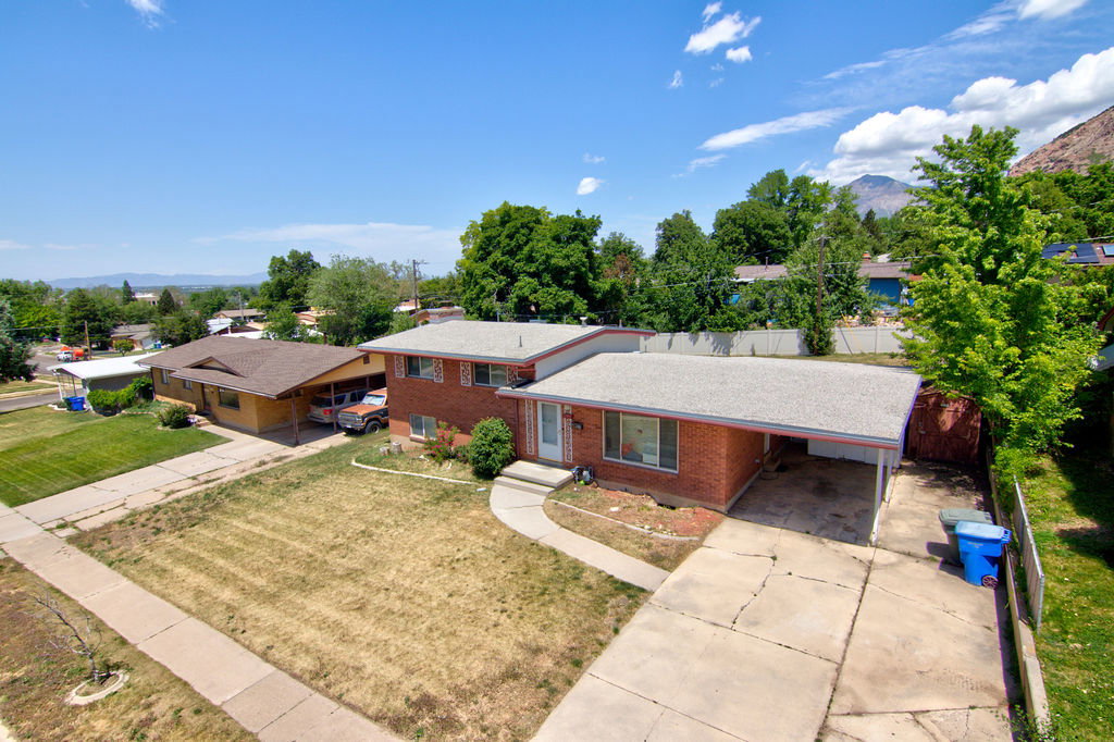 Brick exterior home featuring an attached carport, concrete driveway, and front walkway leading to the entry