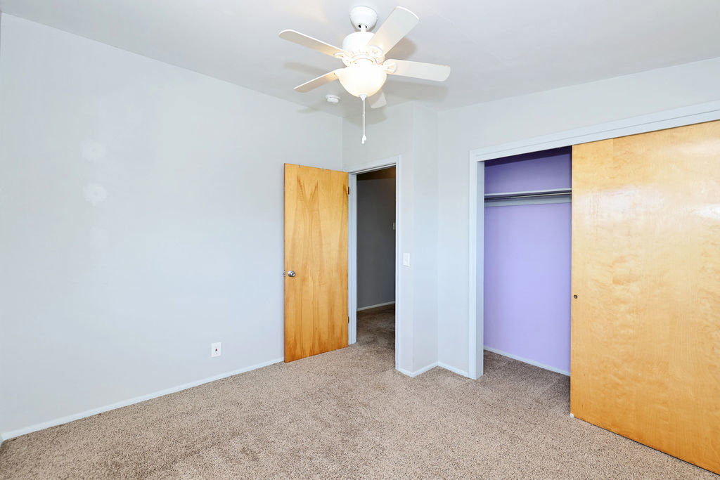 Bedroom featuring light gray walls, textured carpeting, and a ceiling fan with integrated lighting