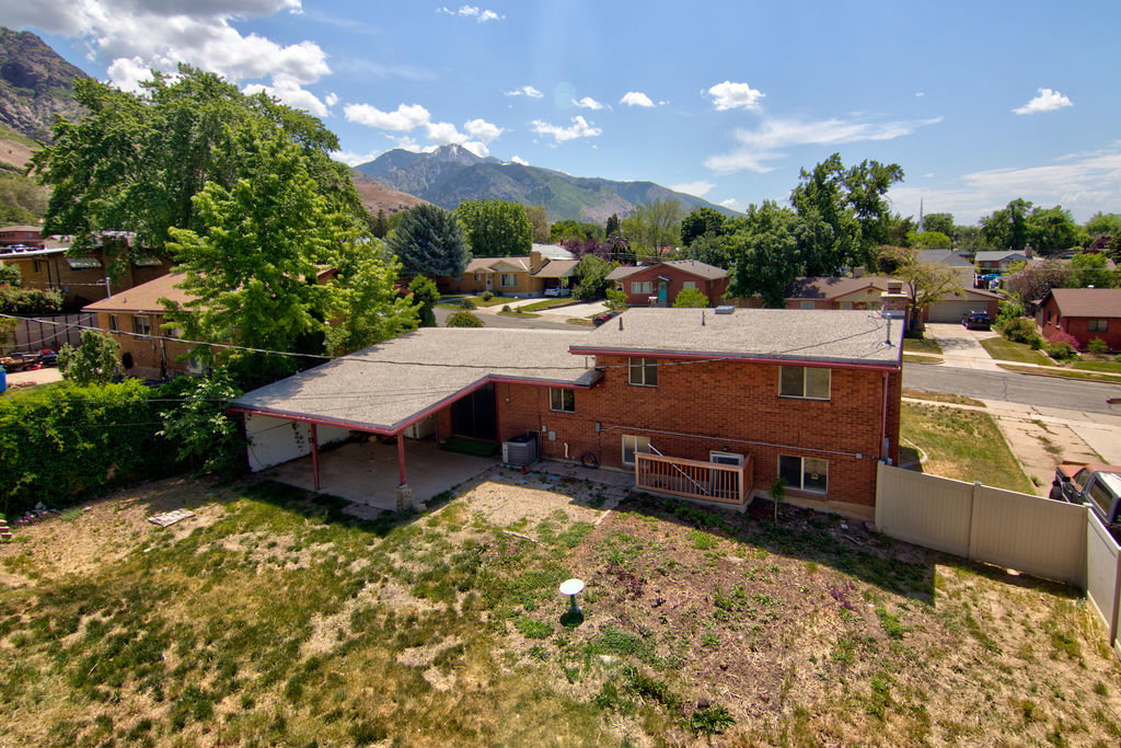 Brick exterior residence featuring a covered patio, rear wood deck, and a spacious backyard