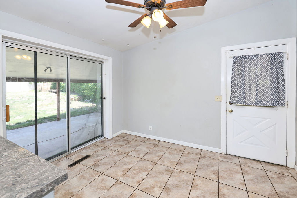 Spacious room featuring tile flooring, light gray walls, and a ceiling fan with light fixture