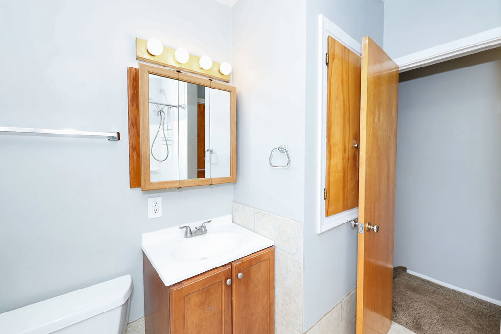 Bathroom vanity with a white countertop sink and wood-finish cabinetry