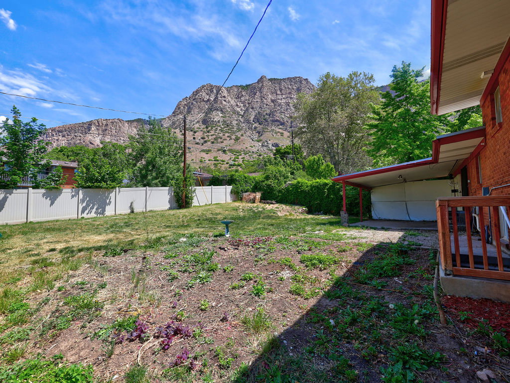 Expansive backyard featuring a partial vinyl fence, a covered patio, and a brick exterior
