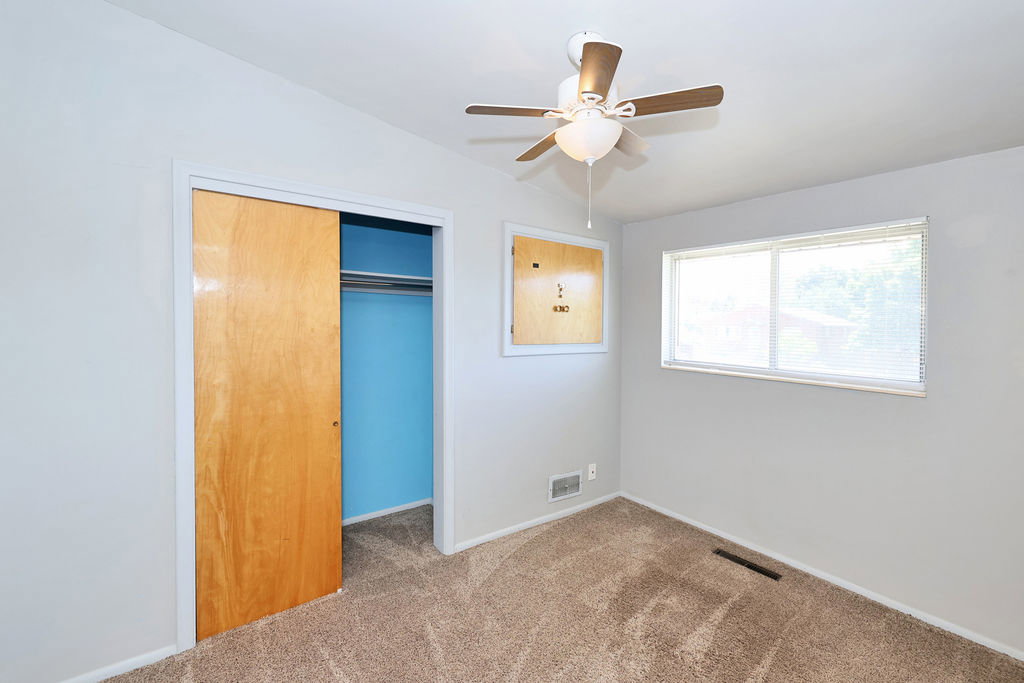 Bedroom featuring neutral wall paint, carpet flooring, a ceiling fan with integrated lighting, a double-pane window with blinds, and a closet with sliding wood-finish doors