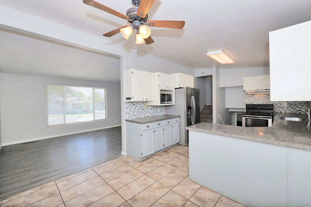 Kitchen featuring granite-style countertops, white cabinetry, and a patterned tile backsplash