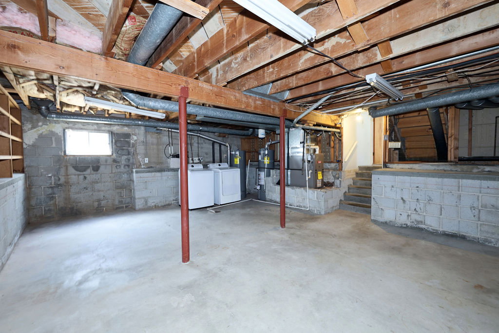 Unfinished basement with exposed wood joists and concrete flooring