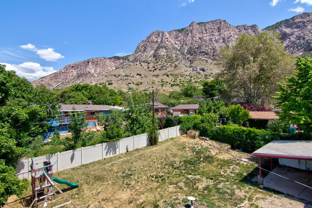 Expansive backyard featuring a white privacy fence and a surrounding mountainous landscape