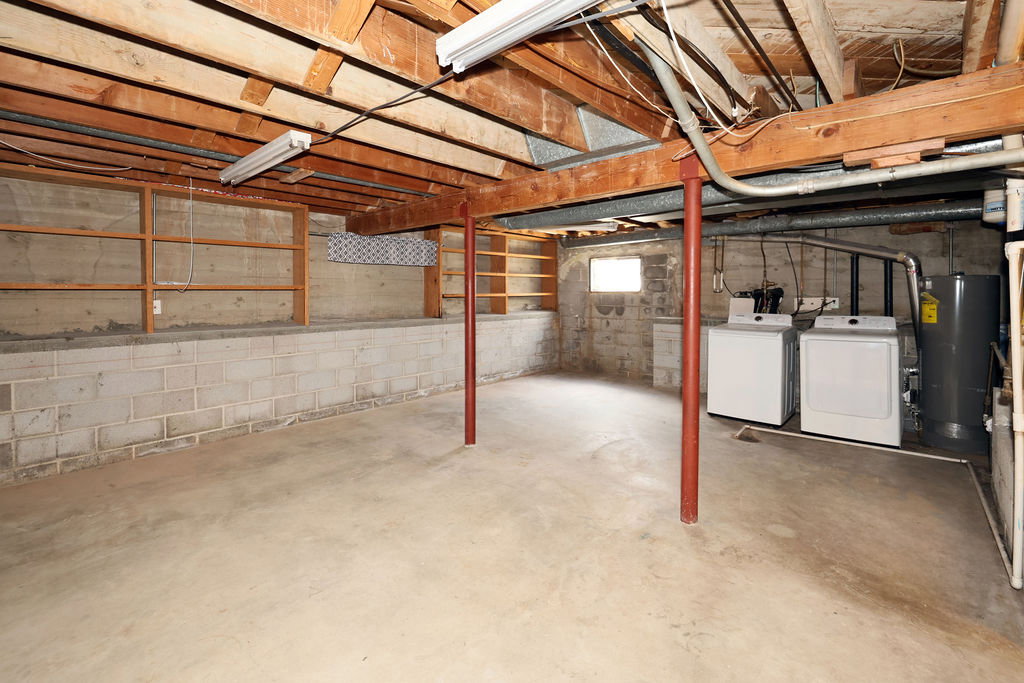 Spacious unfinished basement featuring concrete flooring and exposed ceiling joists