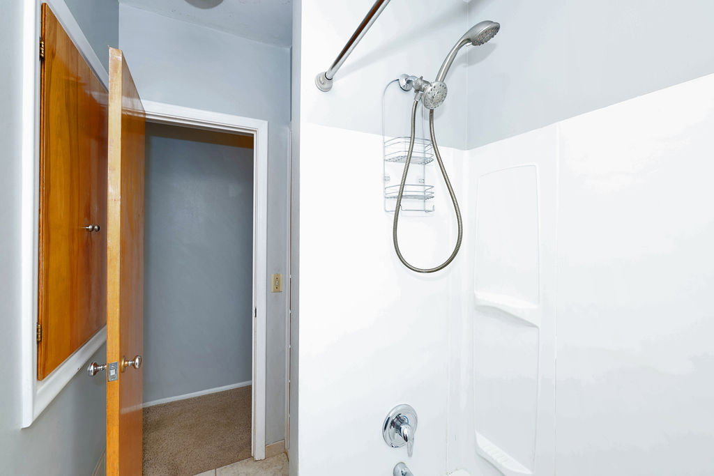 White shower enclosure with integrated shelving and a chrome shower fixture