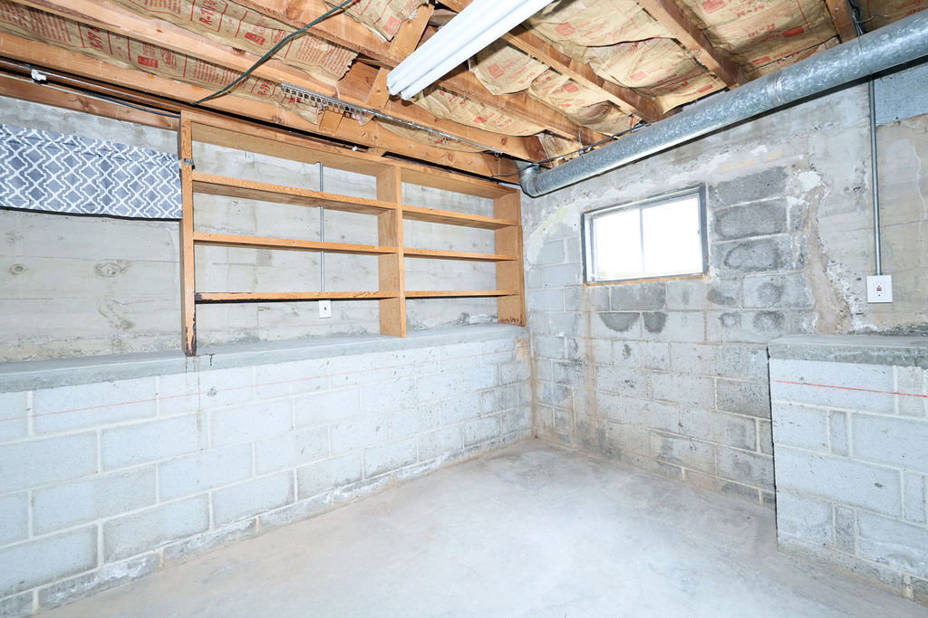 Concrete block walls with an exposed ceiling featuring wood joists and insulation