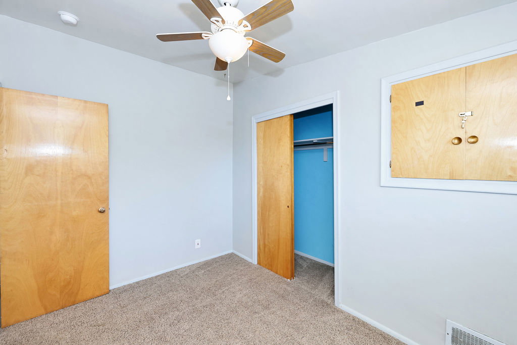 Light grey painted walls with wood-finish doors and a ceiling fan