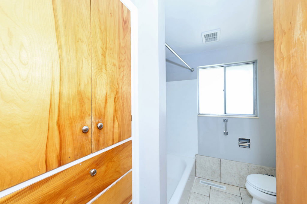 Bathroom featuring a white bathtub, frosted window, and light-toned floor tiling
