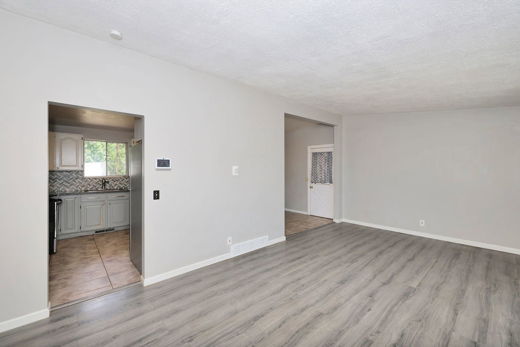 Spacious living area featuring contemporary wood-finish flooring and neutral-toned walls