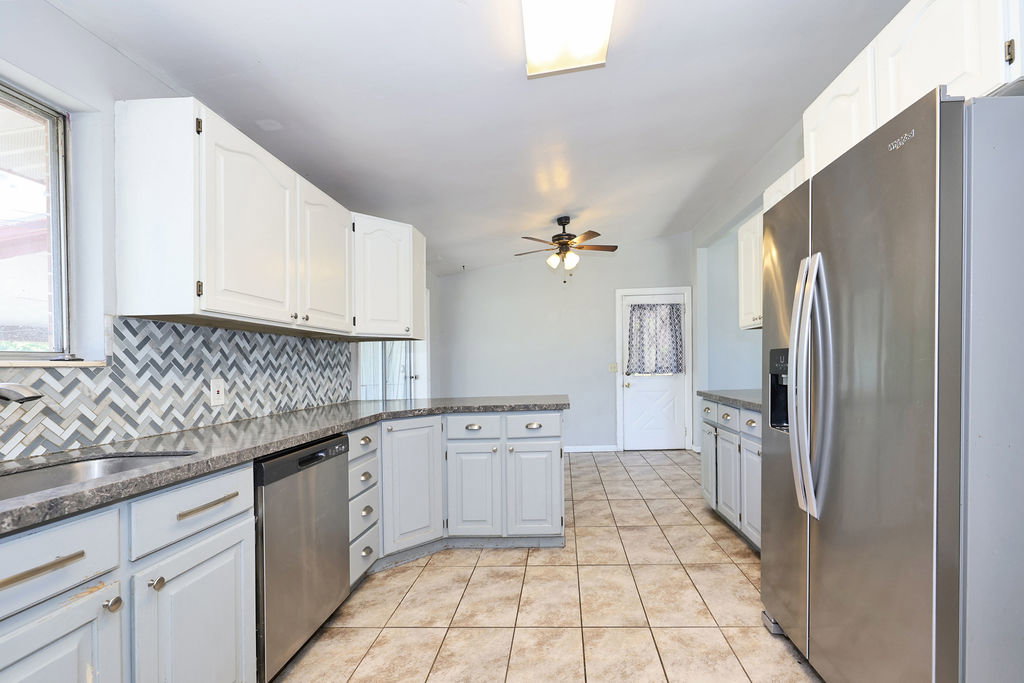 Kitchen featuring white upper cabinetry, light gray lower cabinetry, and a herringbone mosaic tile backsplash