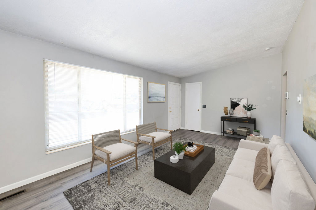 Spacious living area featuring a large window with blinds, wood-finish flooring, and a vaulted ceiling