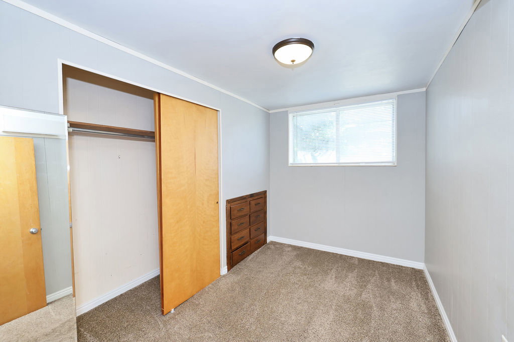 Carpeted room featuring light gray walls, a window with blinds, and a flush-mount ceiling light