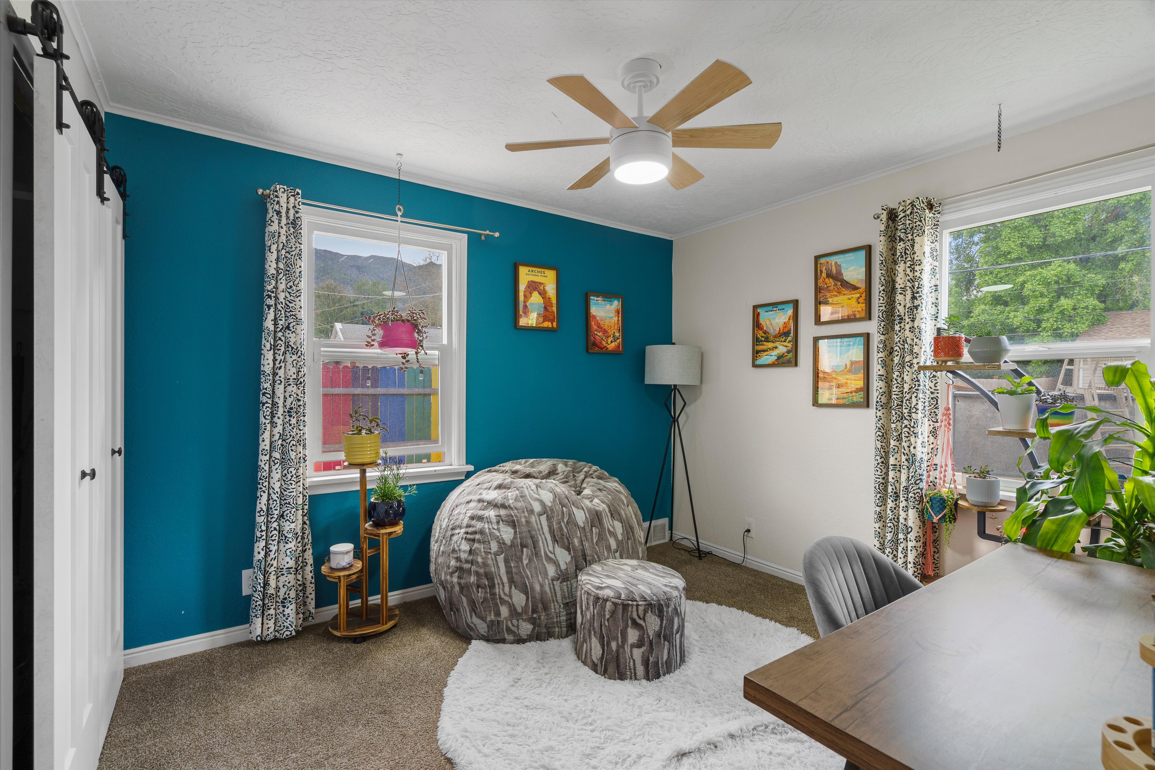 Bright interior space featuring a ceiling fan with light fixture, dual windows, and barn door entry