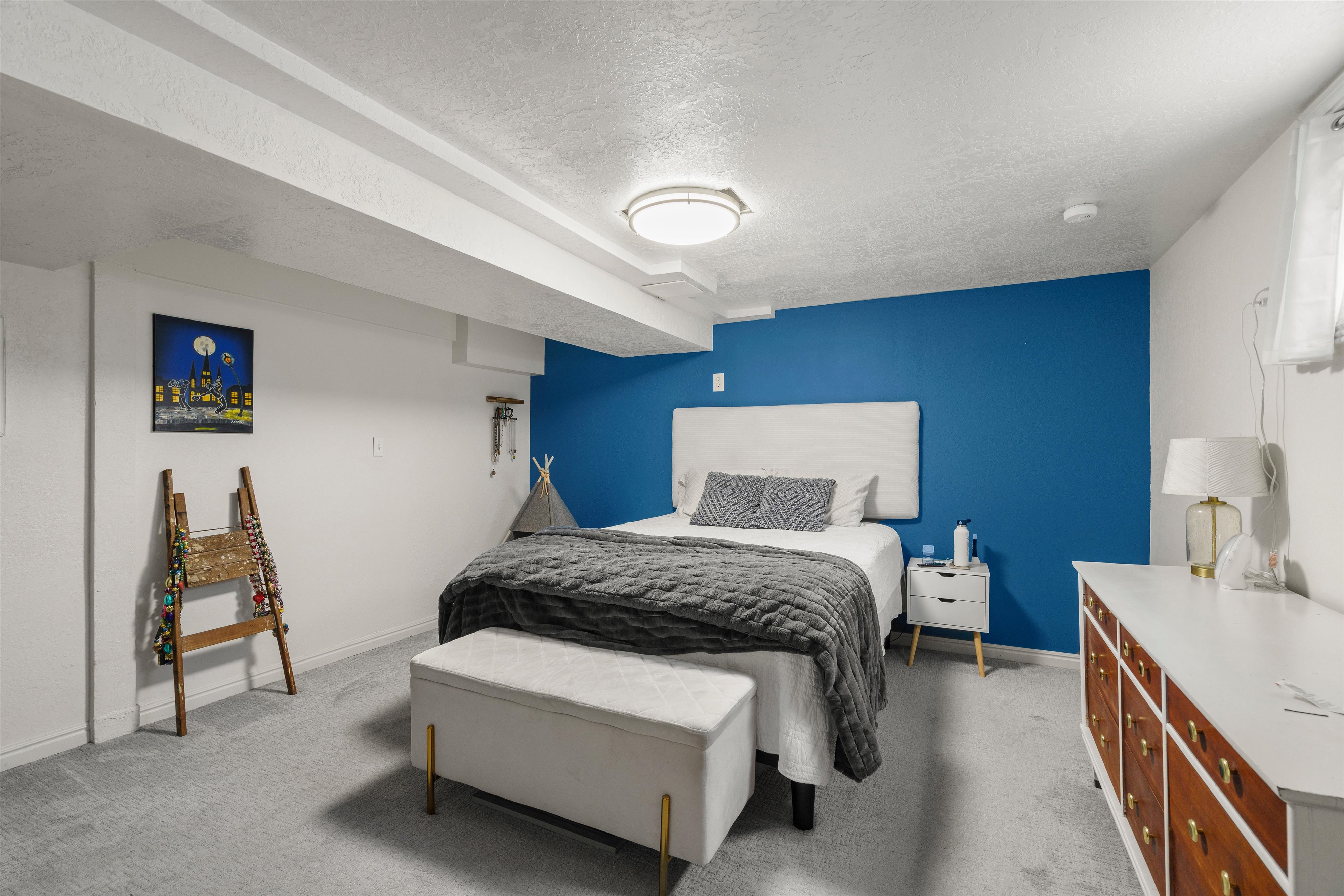 Light gray carpeting and white walls with a blue accent wall