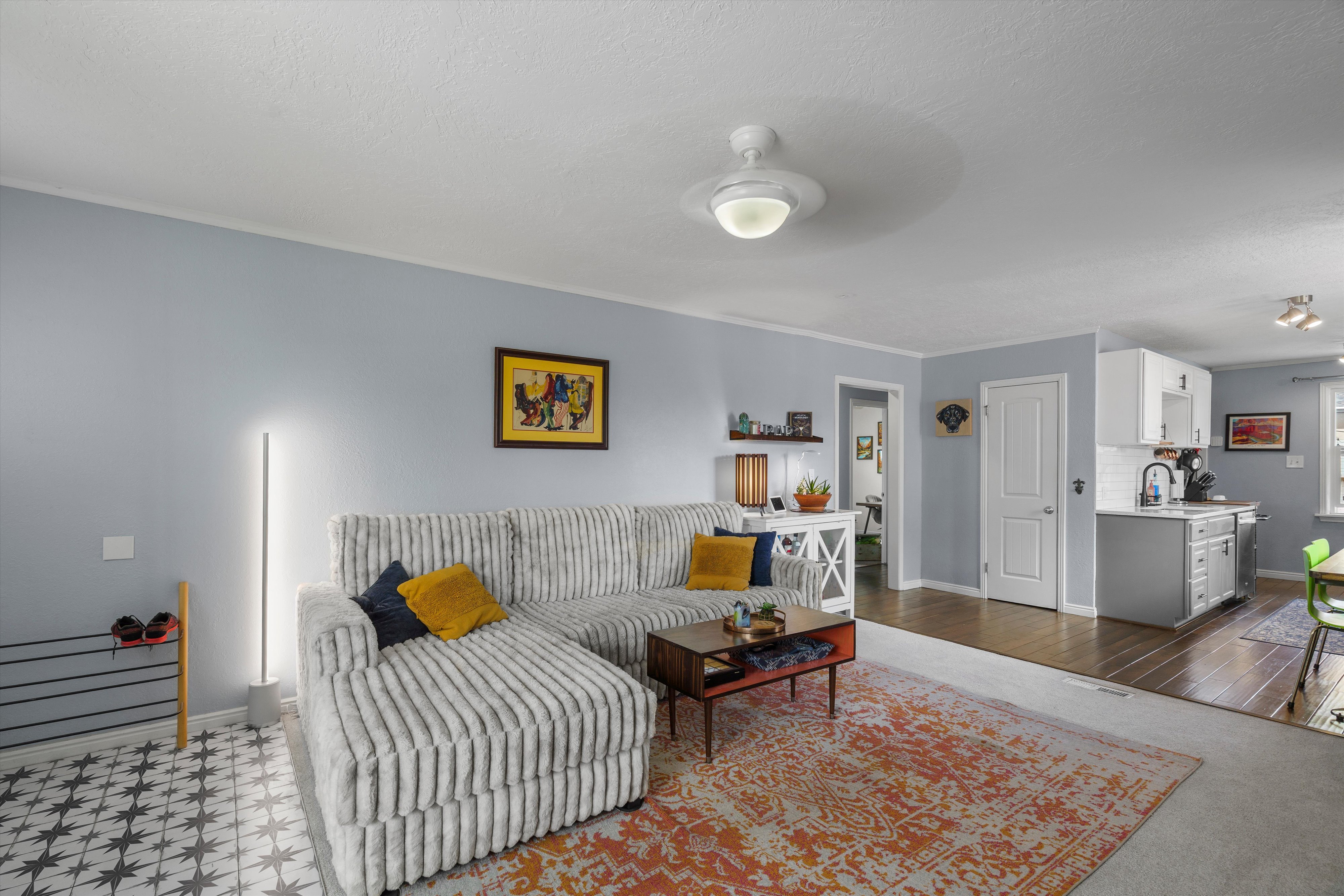 Living area featuring light blue walls and a white ceiling with a ceiling fan