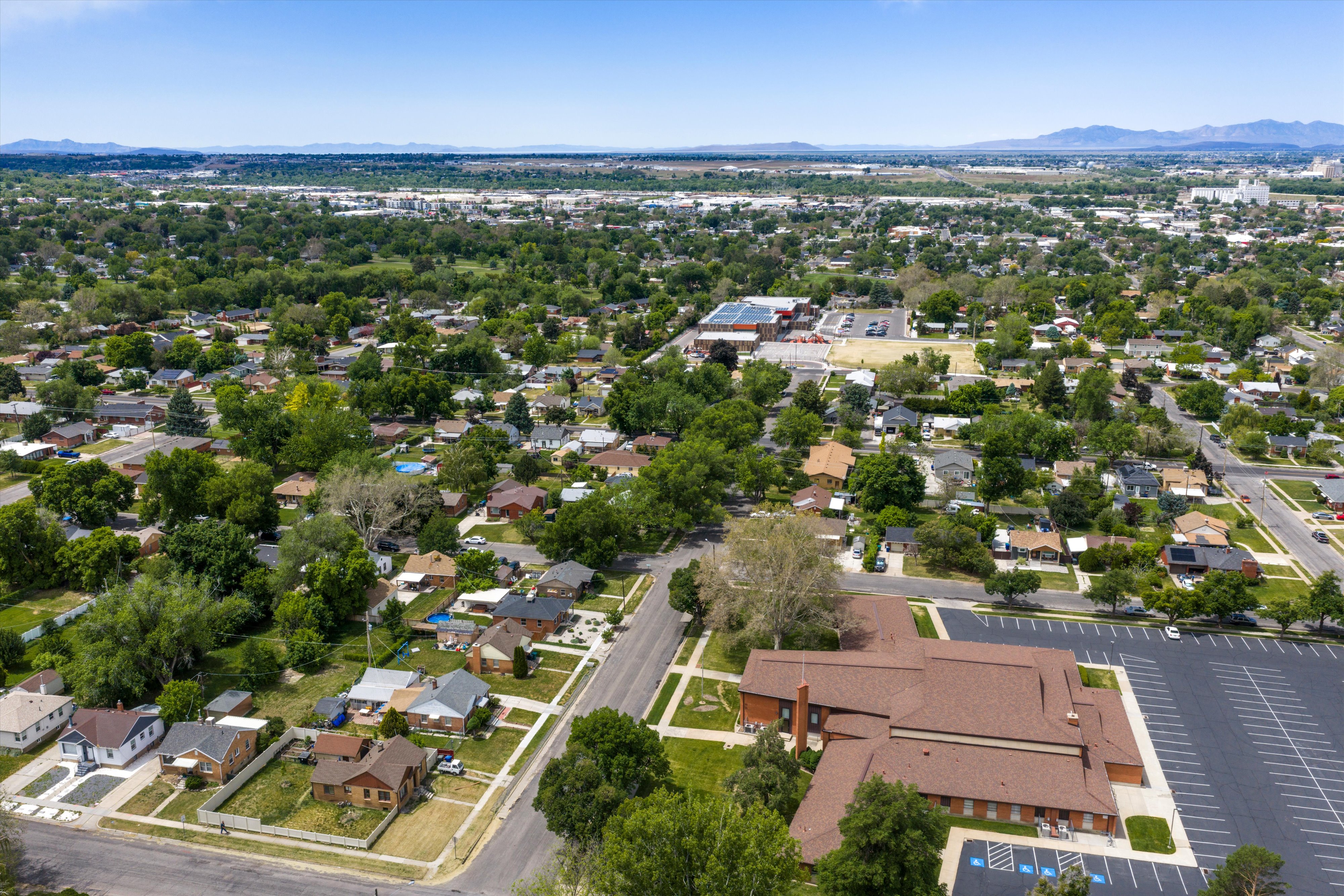 Expansive aerial perspective showcasing a residential neighborhood with varied single-story homes, mature trees, and paved streets