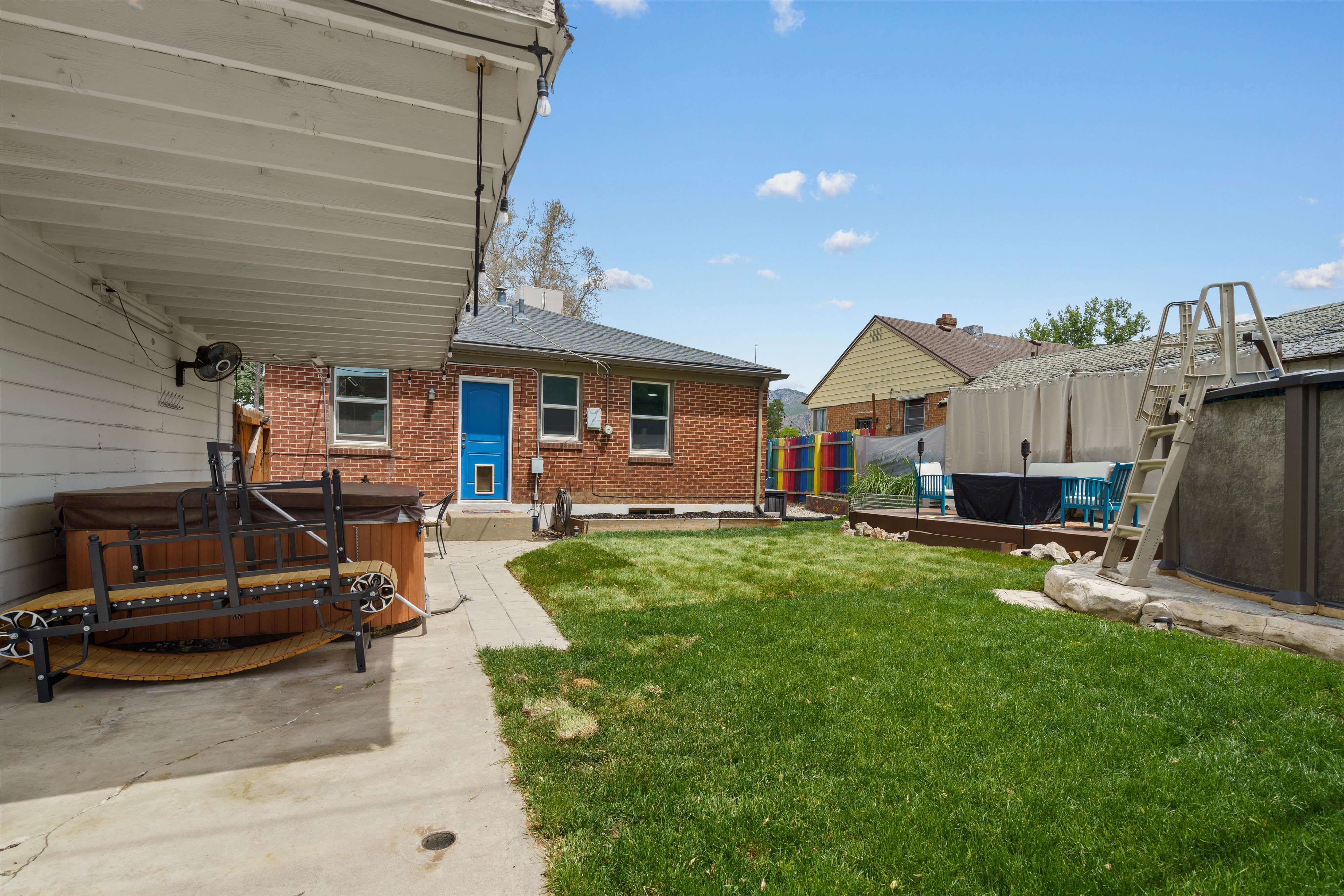 Expansive backyard featuring a covered patio, an integrated spa, and a grass lawn