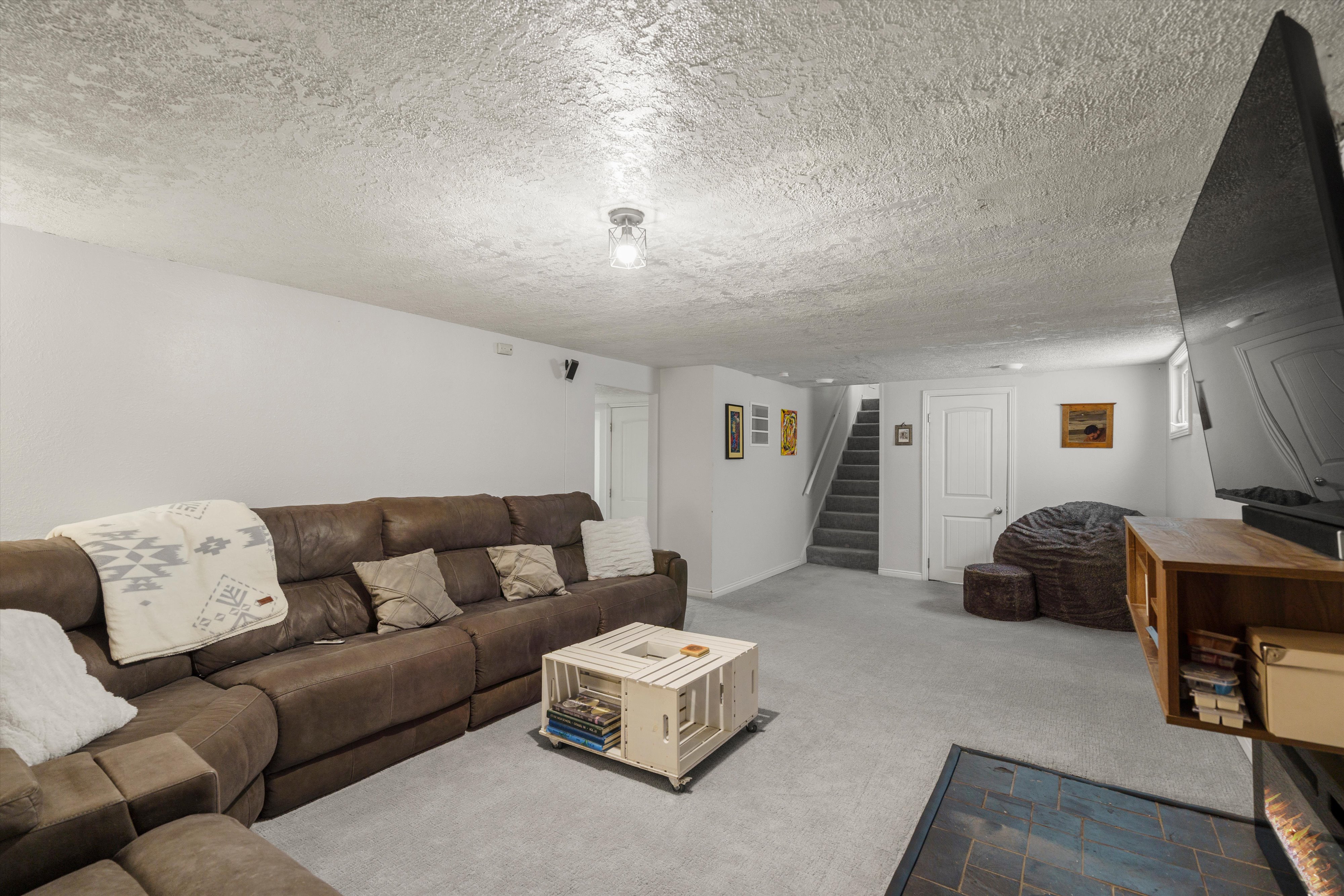 Spacious interior room featuring light gray carpeting, white walls, and a textured ceiling