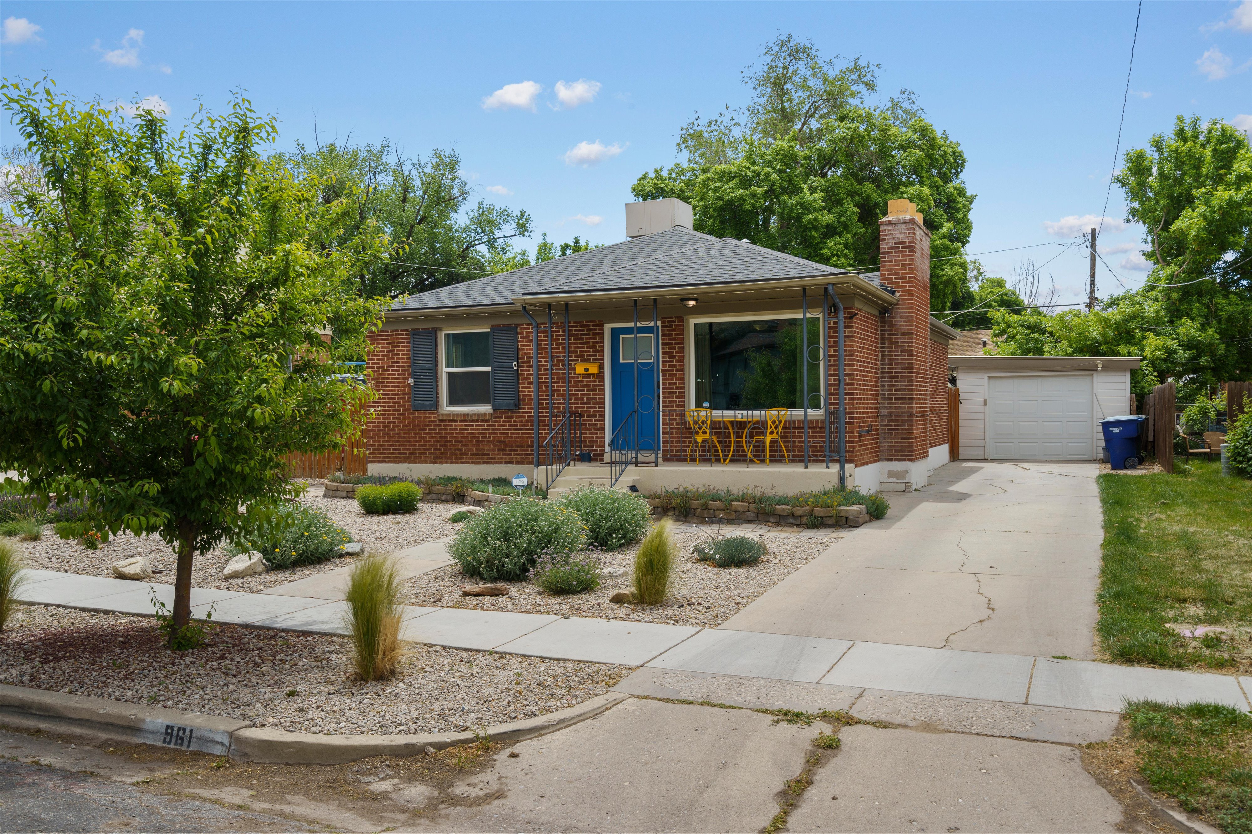 Brick single-story residence featuring a blue entry door and dark shutters