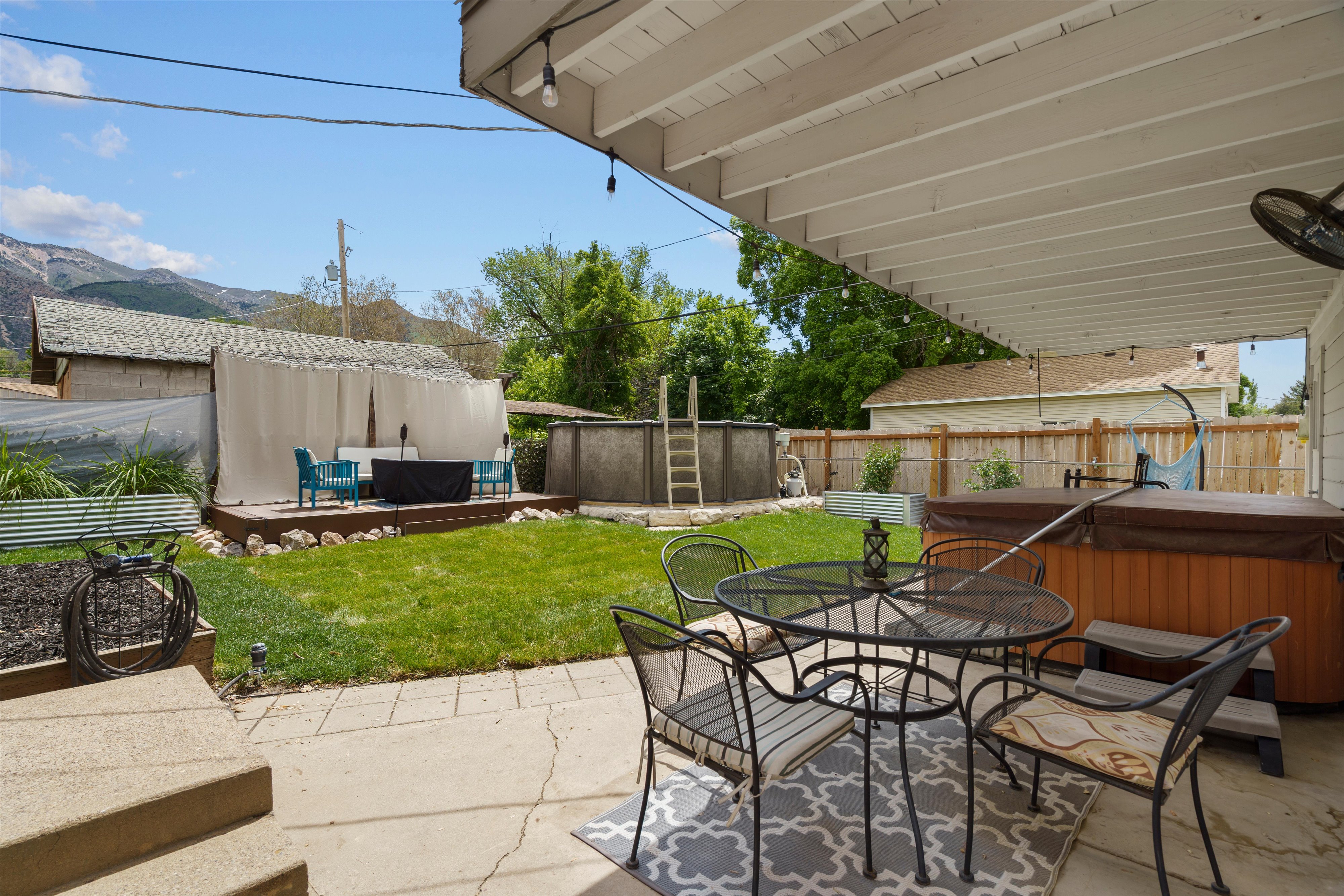 Expansive backyard featuring a covered patio, an above-ground spa, a wooden deck with privacy screens, an above-ground pool, and a manicured lawn