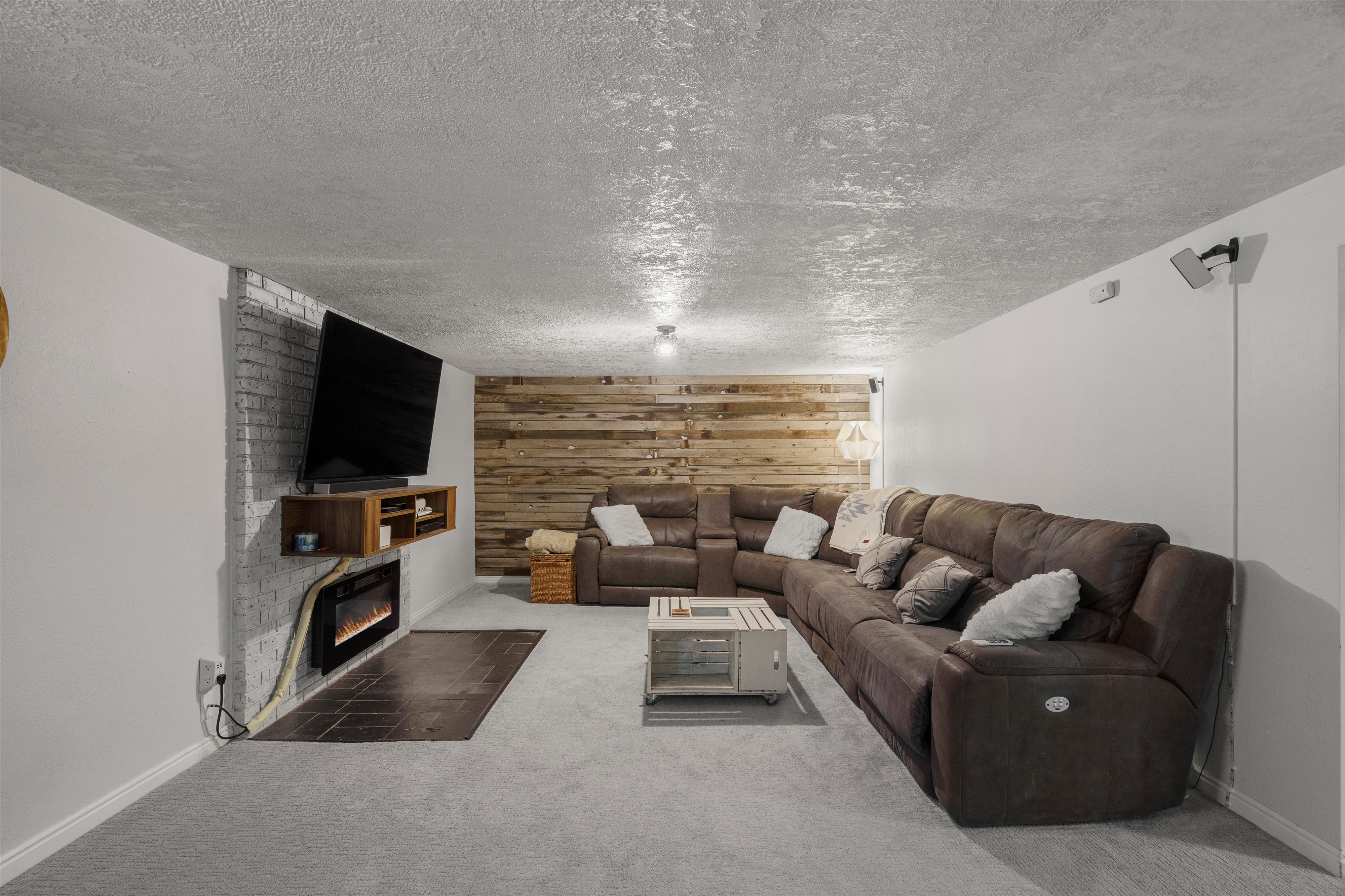 Reclaimed wood accent wall, built-in electric fireplace with tile hearth, and suspended media console