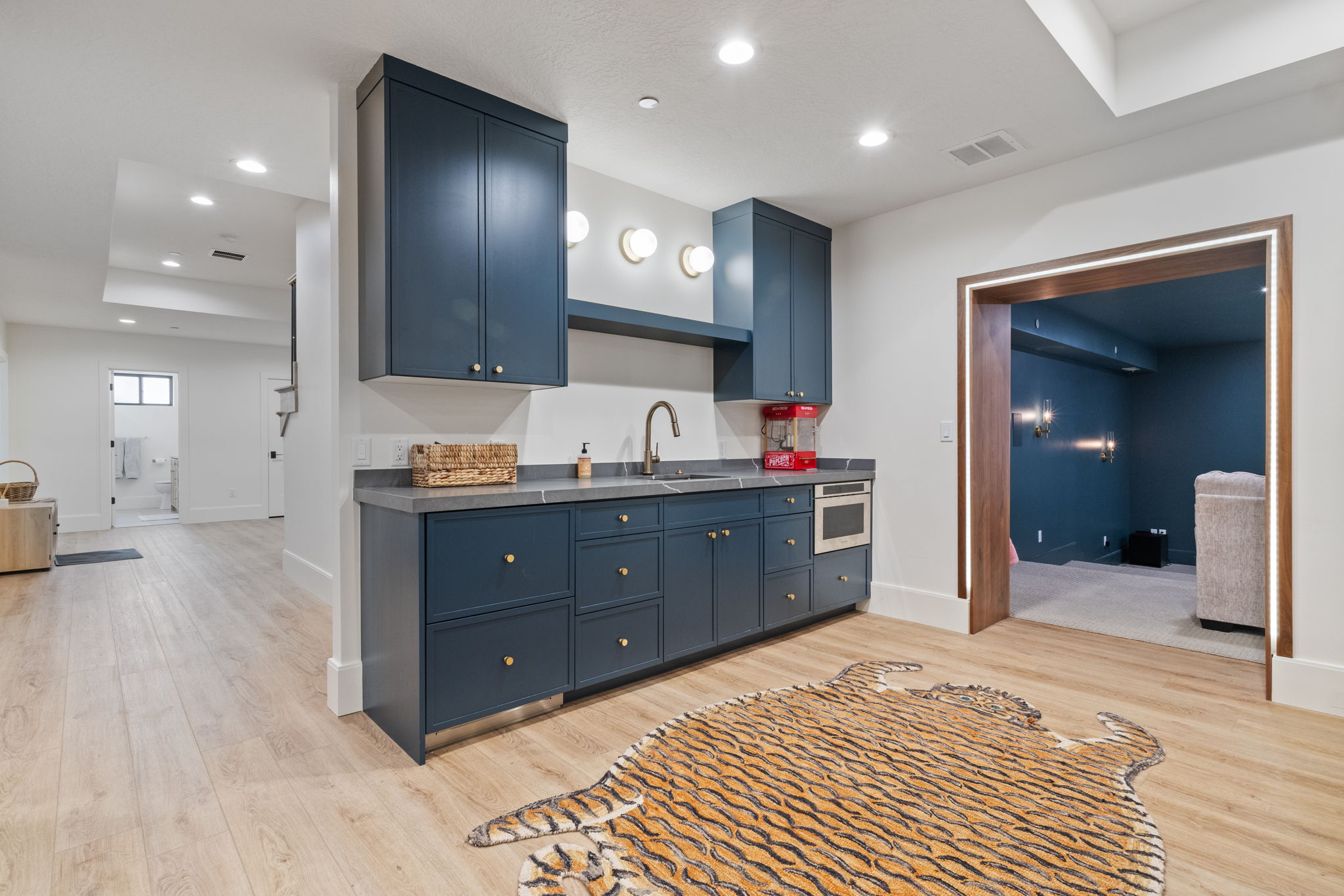 Dedicated wet bar featuring dark blue cabinetry, a built-in microwave, wood-finish flooring, and recessed lighting