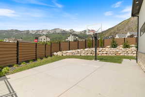 Expansive concrete patio with integrated basketball hoop and a retaining wall featuring natural stone