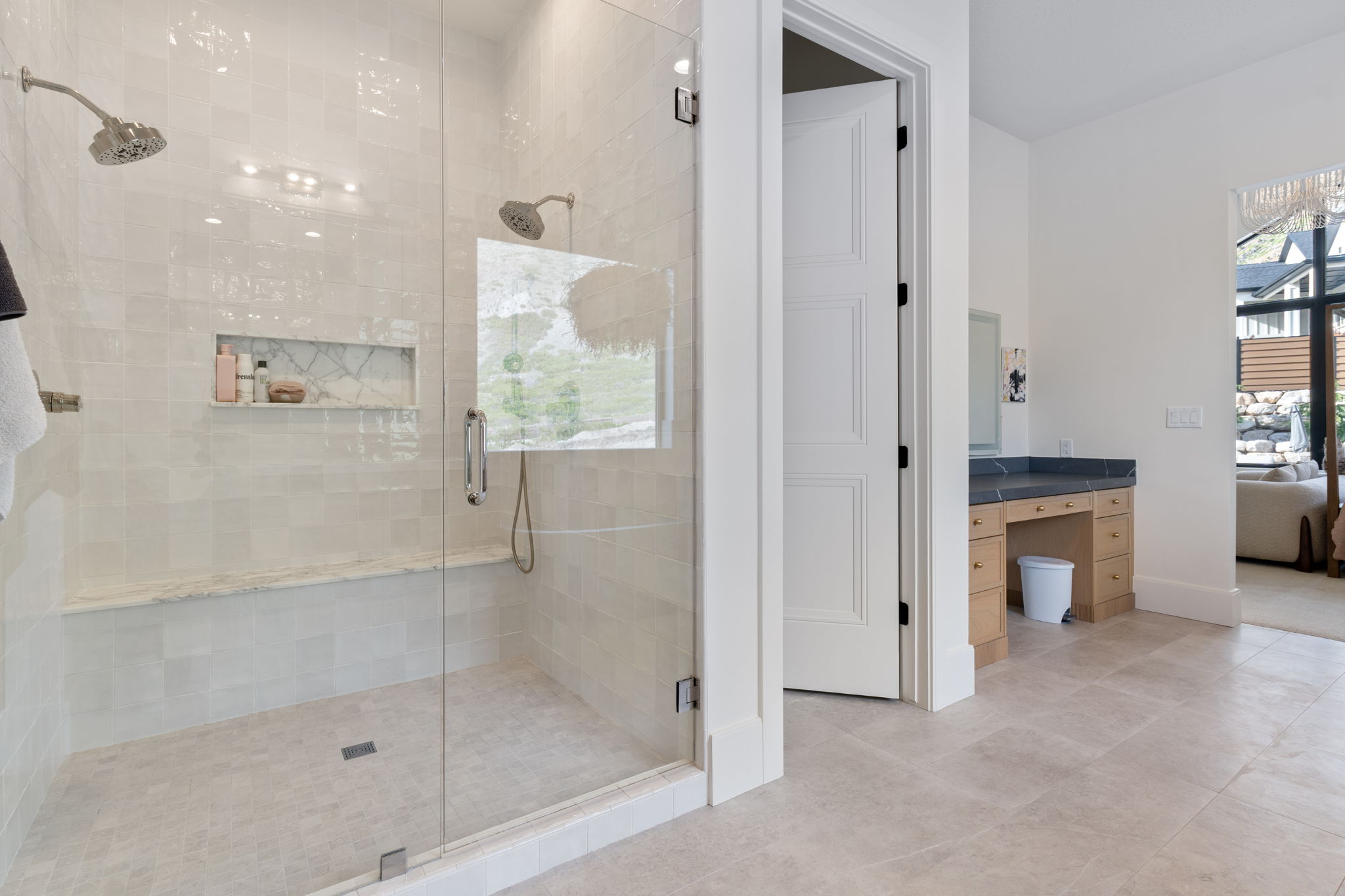 Walk-in shower with dual shower heads, a built-in marble bench, and an integrated tiled niche