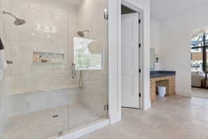 Walk-in shower with dual shower heads, a built-in marble bench, and an integrated tiled niche