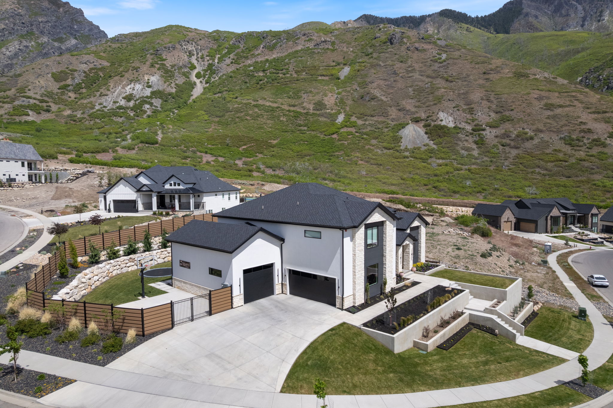 Contemporary residence featuring a dark shingle roof, light-toned exterior siding, and black garage doors