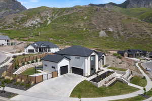 Contemporary residence featuring a dark shingle roof, light-toned exterior siding, and black garage doors