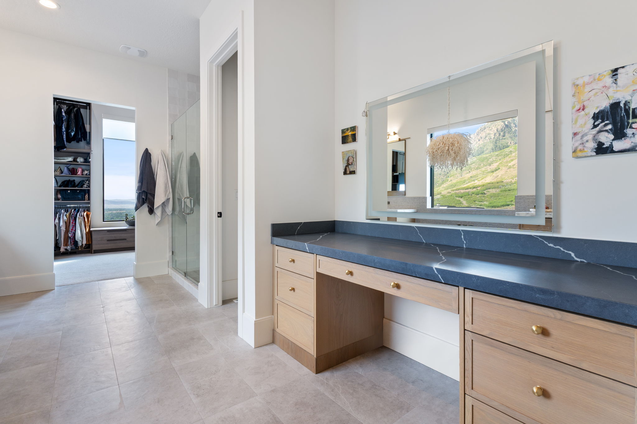 Vanity area featuring a dark countertop with white veining, light wood-finish cabinetry, and gold-tone hardware
