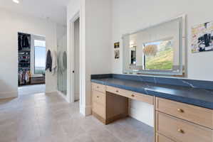 Vanity area featuring a dark countertop with white veining, light wood-finish cabinetry, and gold-tone hardware