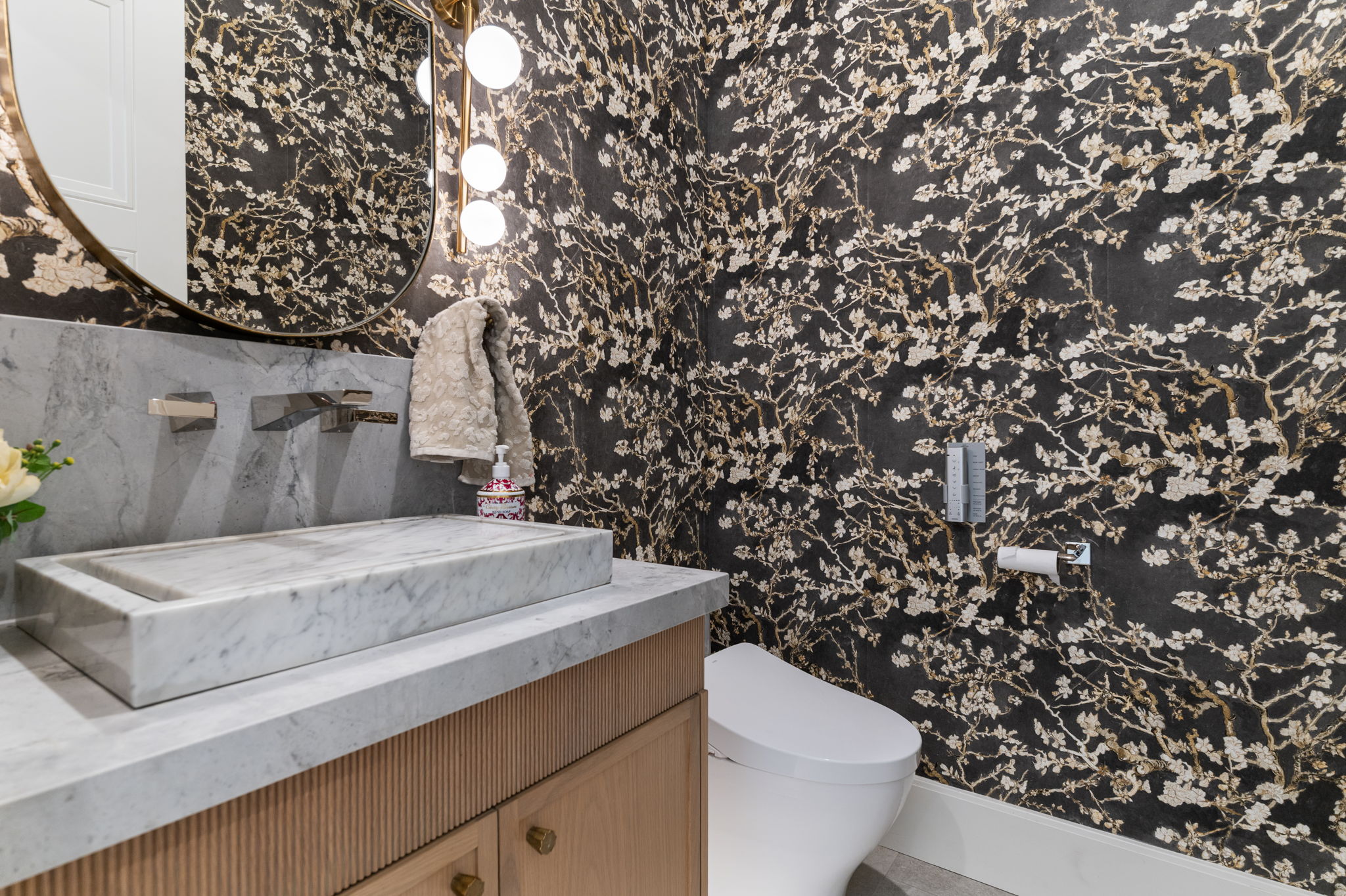 Powder room featuring a rectangular vessel sink, wall-mounted faucet, and a large round mirror with integrated lighting