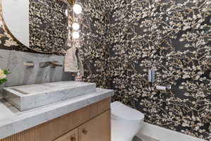 Powder room featuring a rectangular vessel sink, wall-mounted faucet, and a large round mirror with integrated lighting