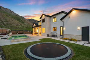 Expansive backyard featuring a built-in trampoline, concrete patio, and a swimming pool with integrated spa