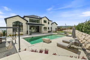Expansive outdoor living area featuring a rectangular swimming pool with a connected hot tub