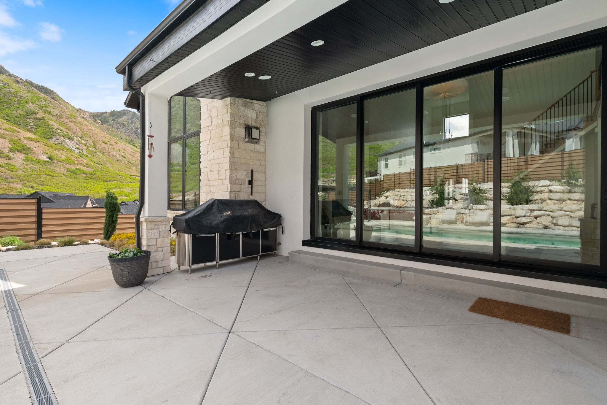 Expansive concrete patio featuring a built-in outdoor kitchen with stone detailing