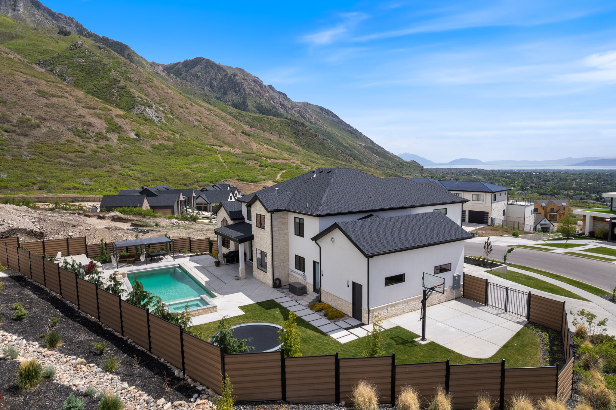 Modern residence featuring a stucco and stone exterior, a private swimming pool with a connected spa, and an integrated basketball court