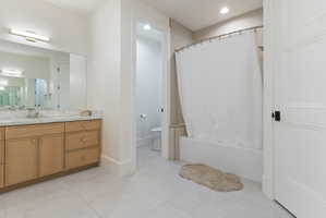 Bathroom featuring a light wood-finish vanity with a stone countertop, an integrated sink, and a large mirror