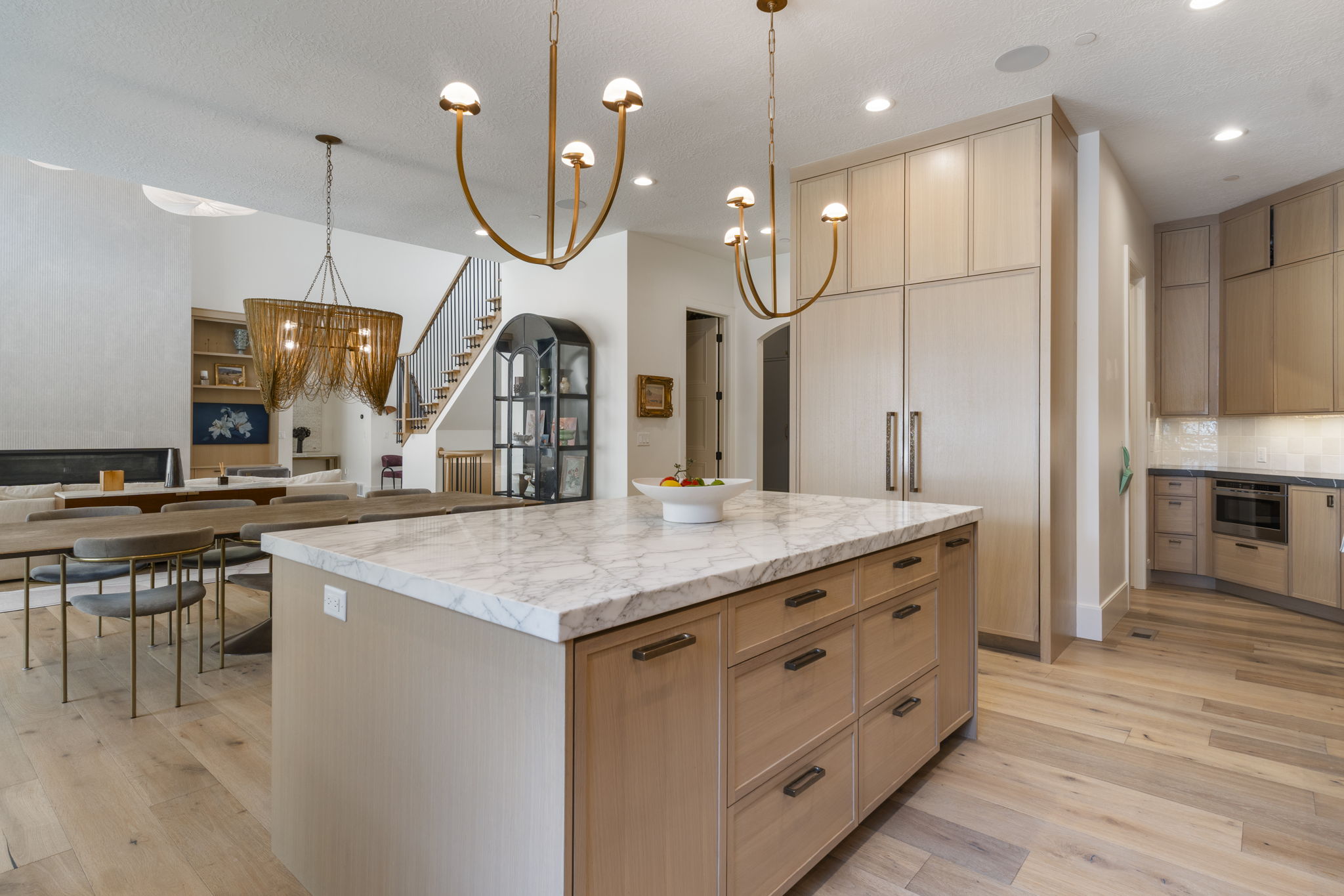 Expansive kitchen island with a marble countertop and white oak cabinetry